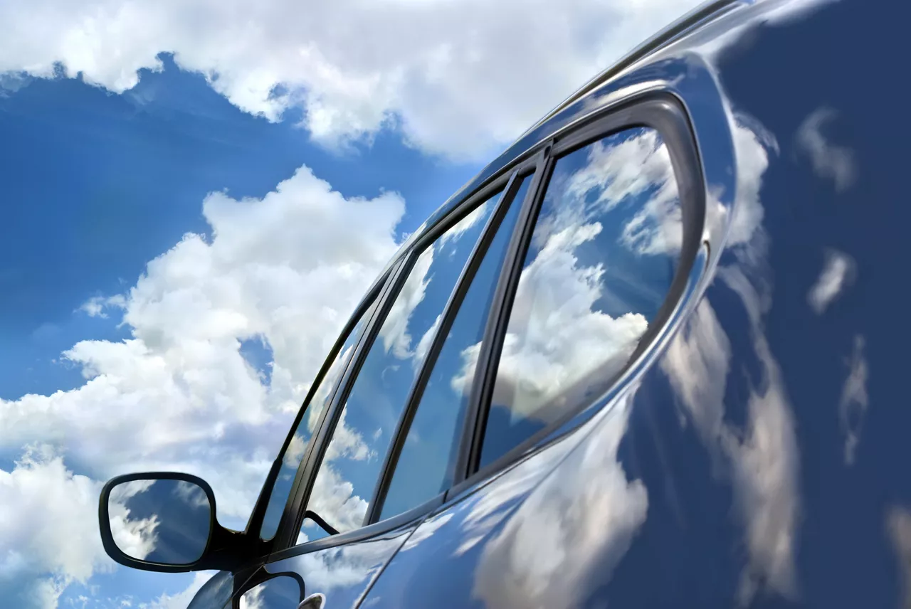 Close up of a car from side with blue sky and cloud in background. 