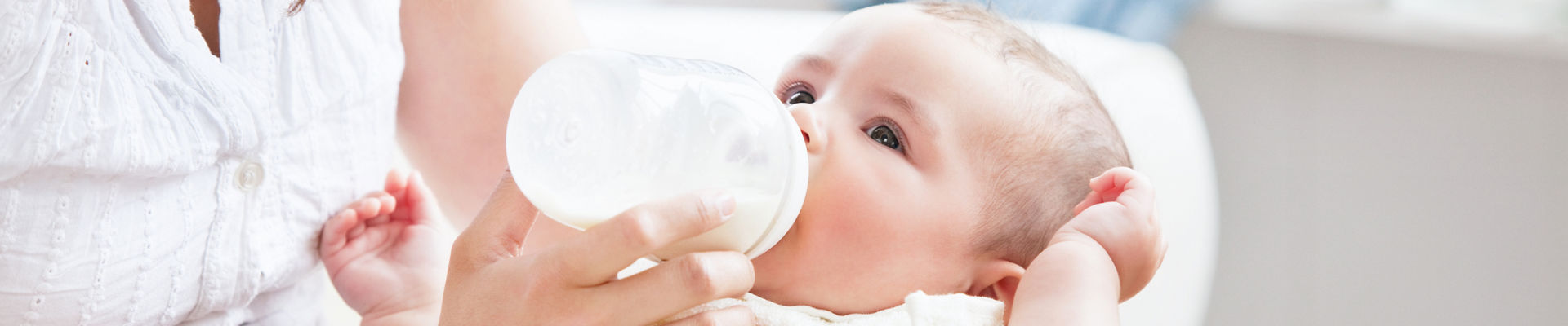 Mother feeding infant from baby bottle