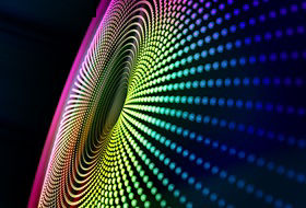 Digital generated image of multicolored particles forming eye shape against black background.