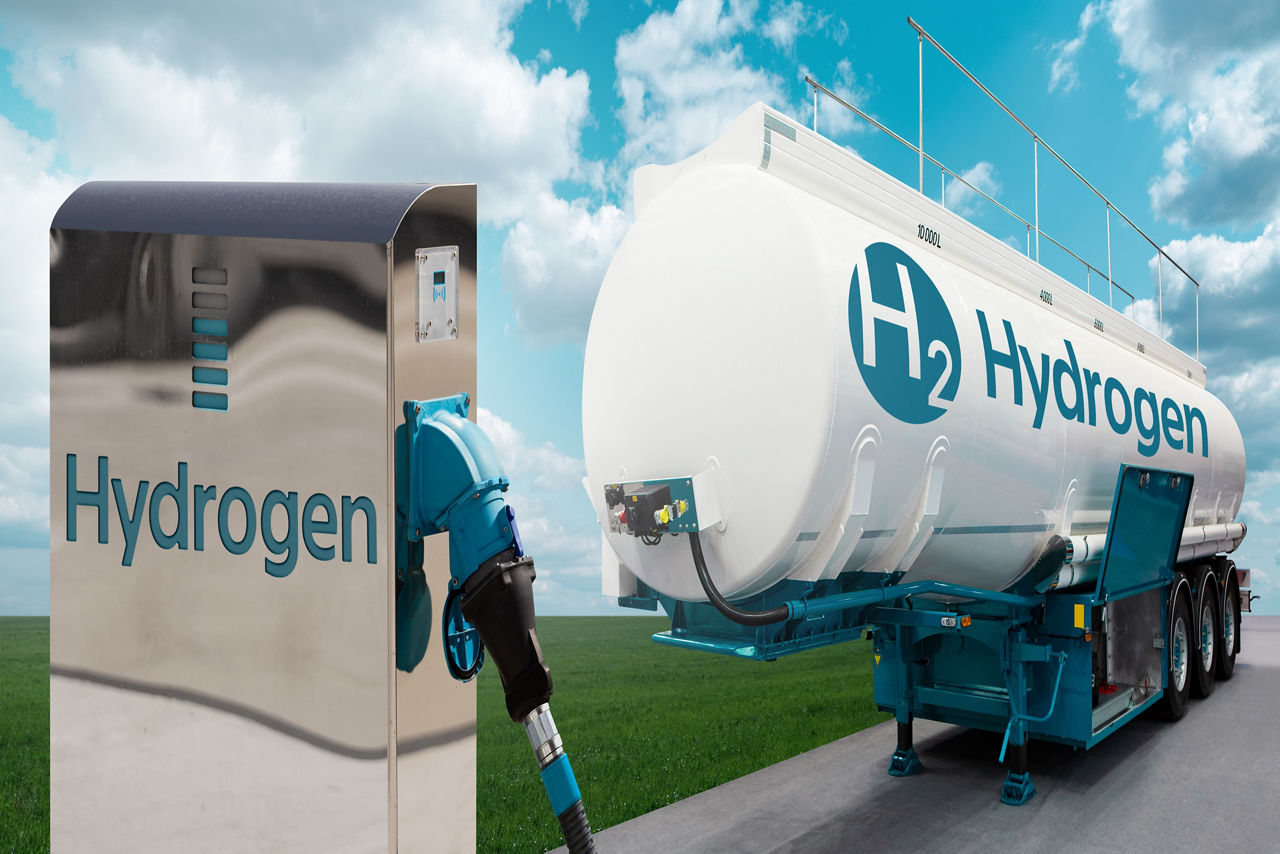 Tank trailer with hydrogen and H2 filling station on the background of a green field and blue sky. Renewable energy