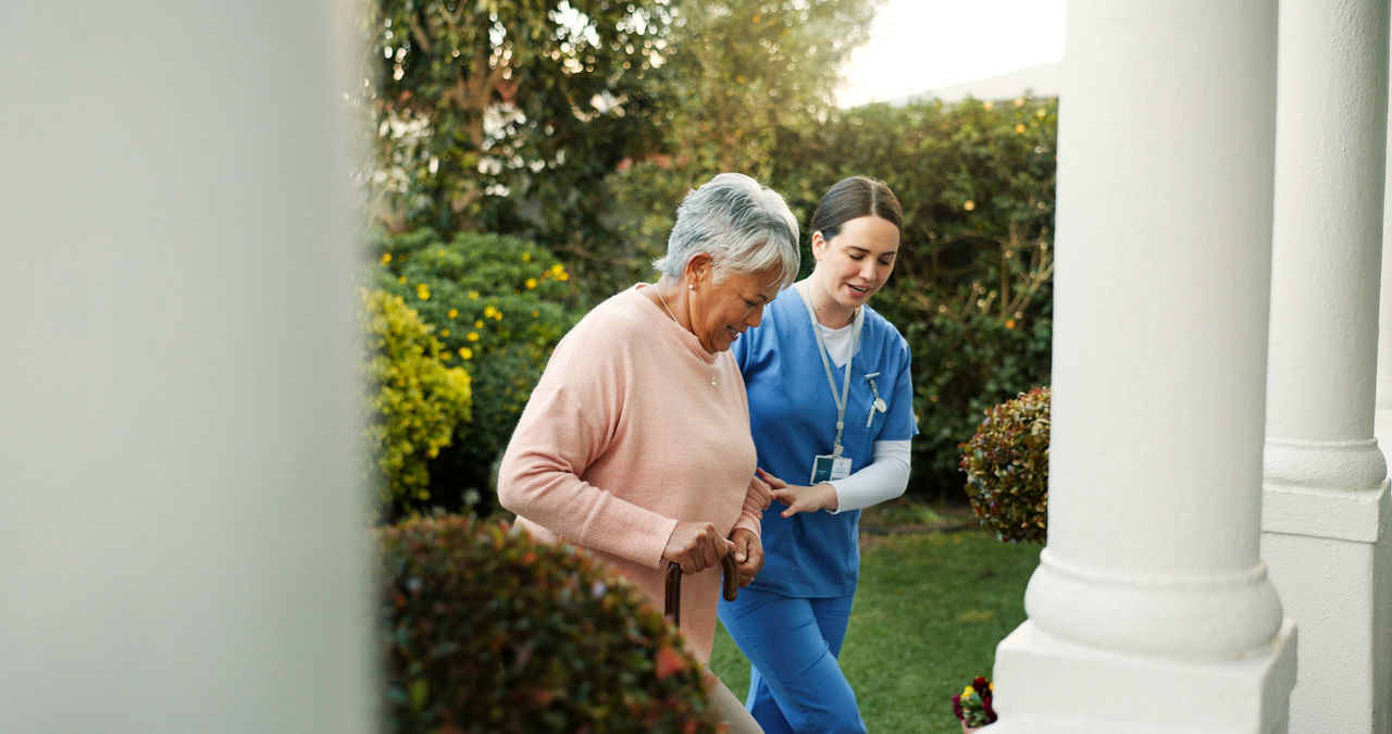 Retirement home, caregiver and senior woman with walking stick outdoor for mobility support, rehabilitation or healing. Assisted living, nurse and elderly person with cane for recovery and assistance.