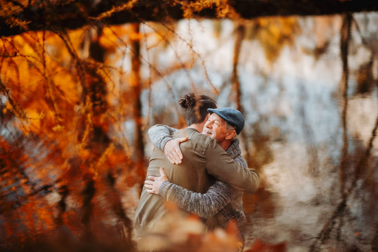 Grandad and grandson hugging in the middle of autumn park. Fall season.