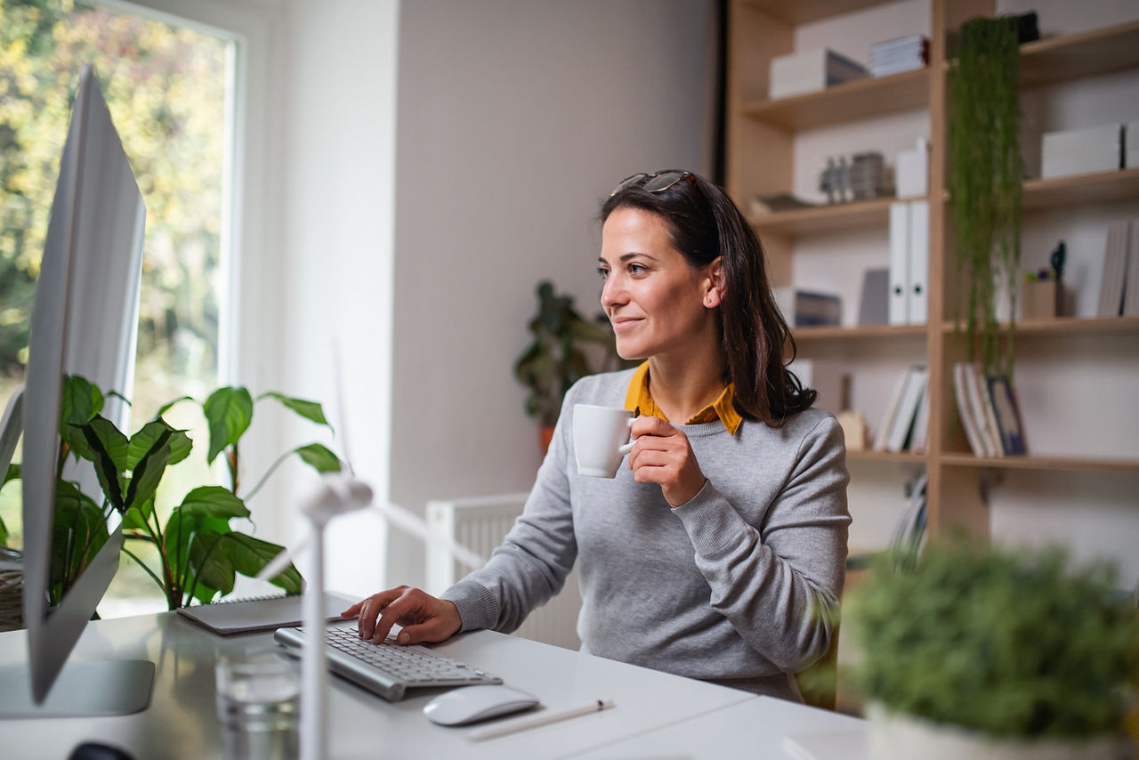 Attractive businesswoman sitting at the desk indoors in office, working with computer.