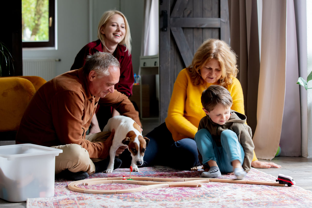 grandparents play the railway with their grandson at home.