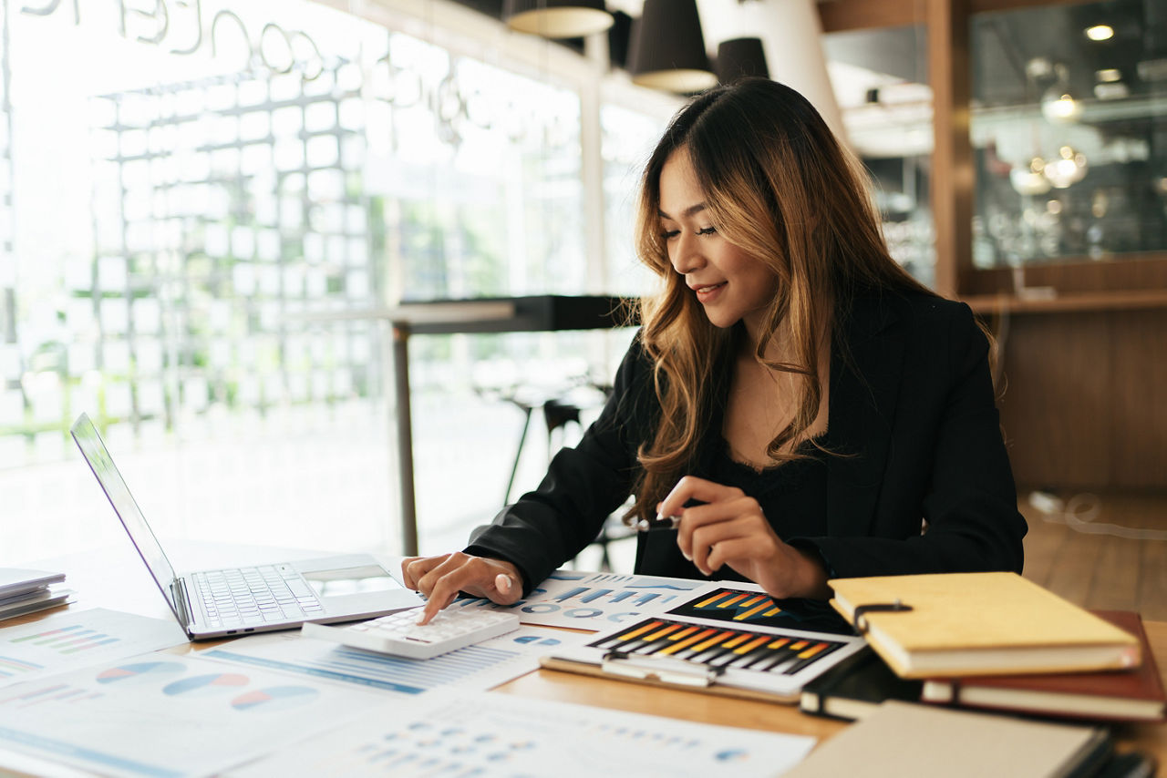 Smiling Young Asian Business women working with calculator, business document and laptop computer notebook,financial inspector and secretary making report,Internal Revenue Service checking document.