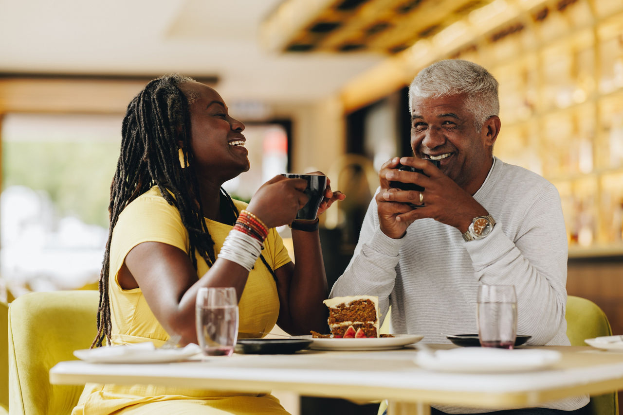 Happy senior couple laughing cheerfully while having coffee together in a cafe. Carefree senior couple having a good time in a restaurant. Mature couple enjoying their retirement together.