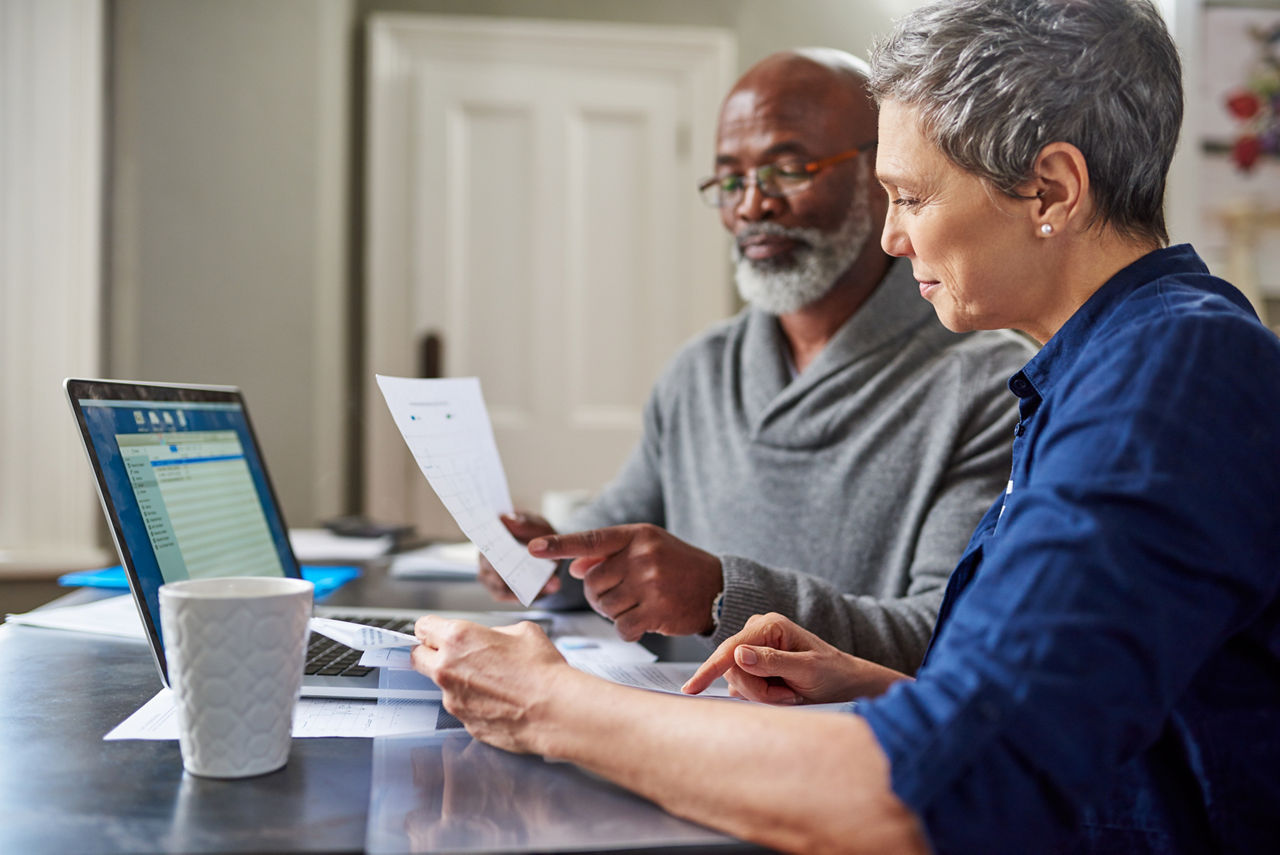 Laptop, documents and finance with a senior couple busy on a budget review in the home together. Accounting, taxes or investment planning with a mature man and woman looking at insurance or savings.