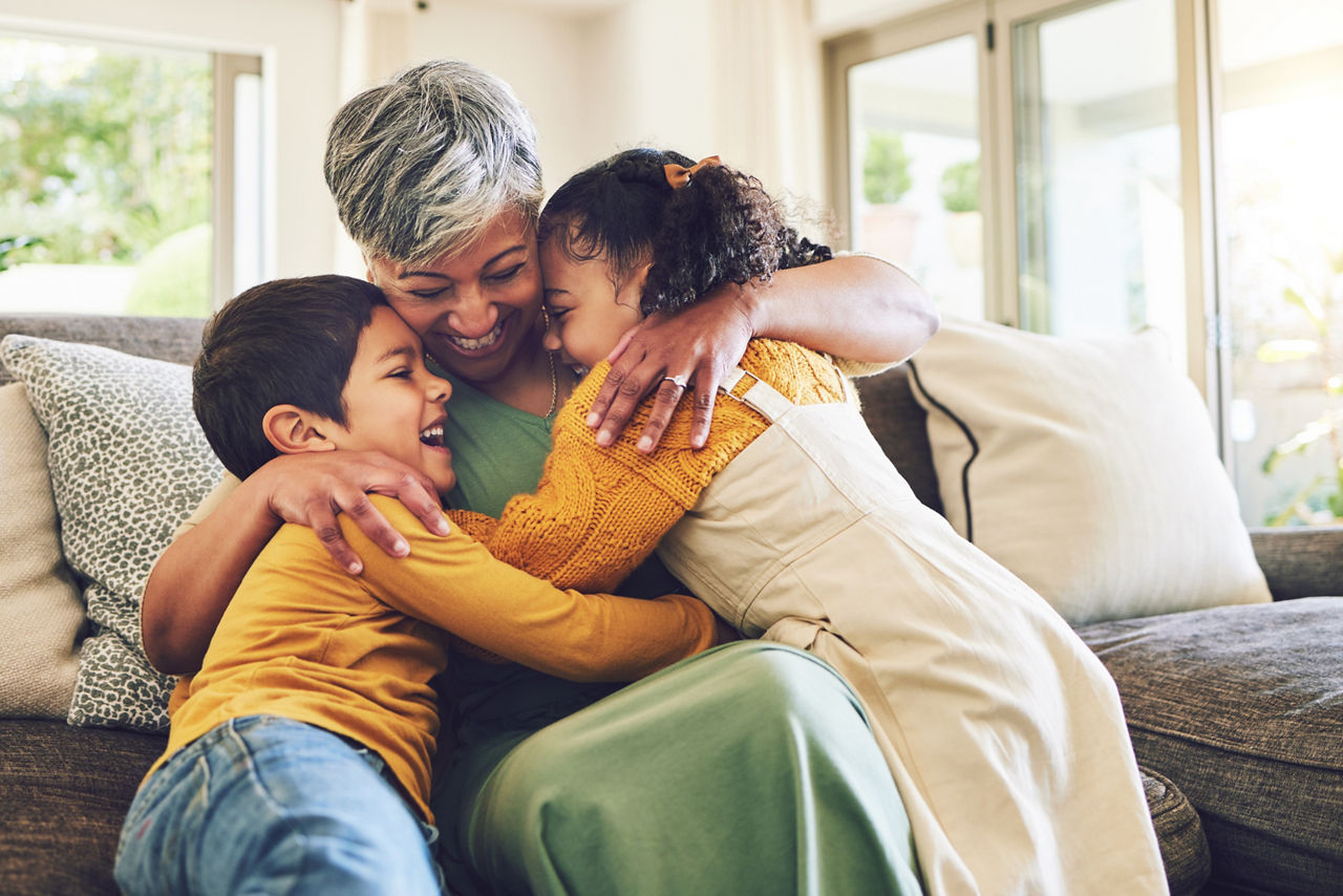 Hug, grandma or happy kids on a sofa with love enjoying quality bonding time together in family home. Smile, affection or senior grandmother relaxing with young children siblings on house couch.