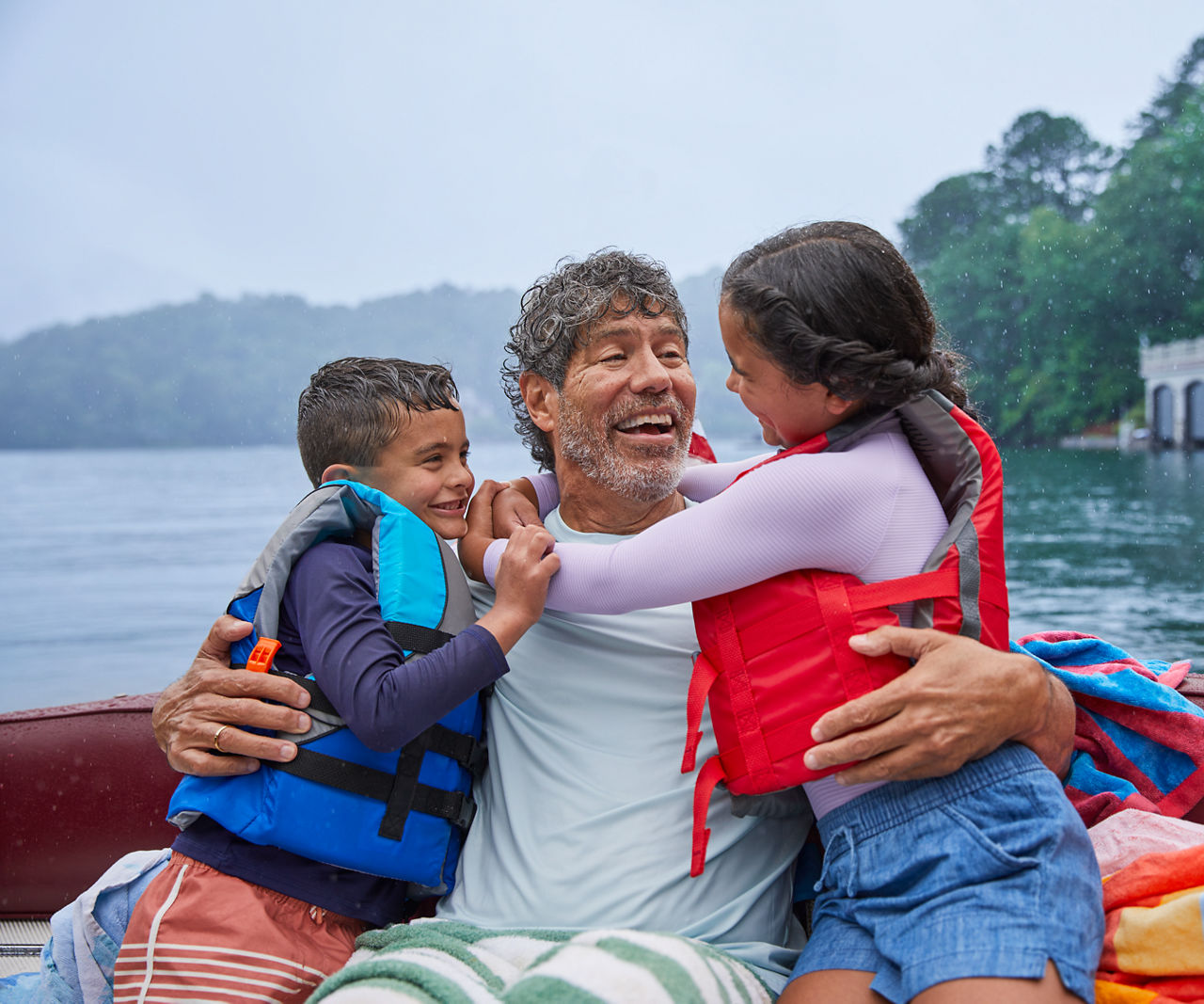 Dad holding two young children in life vests.