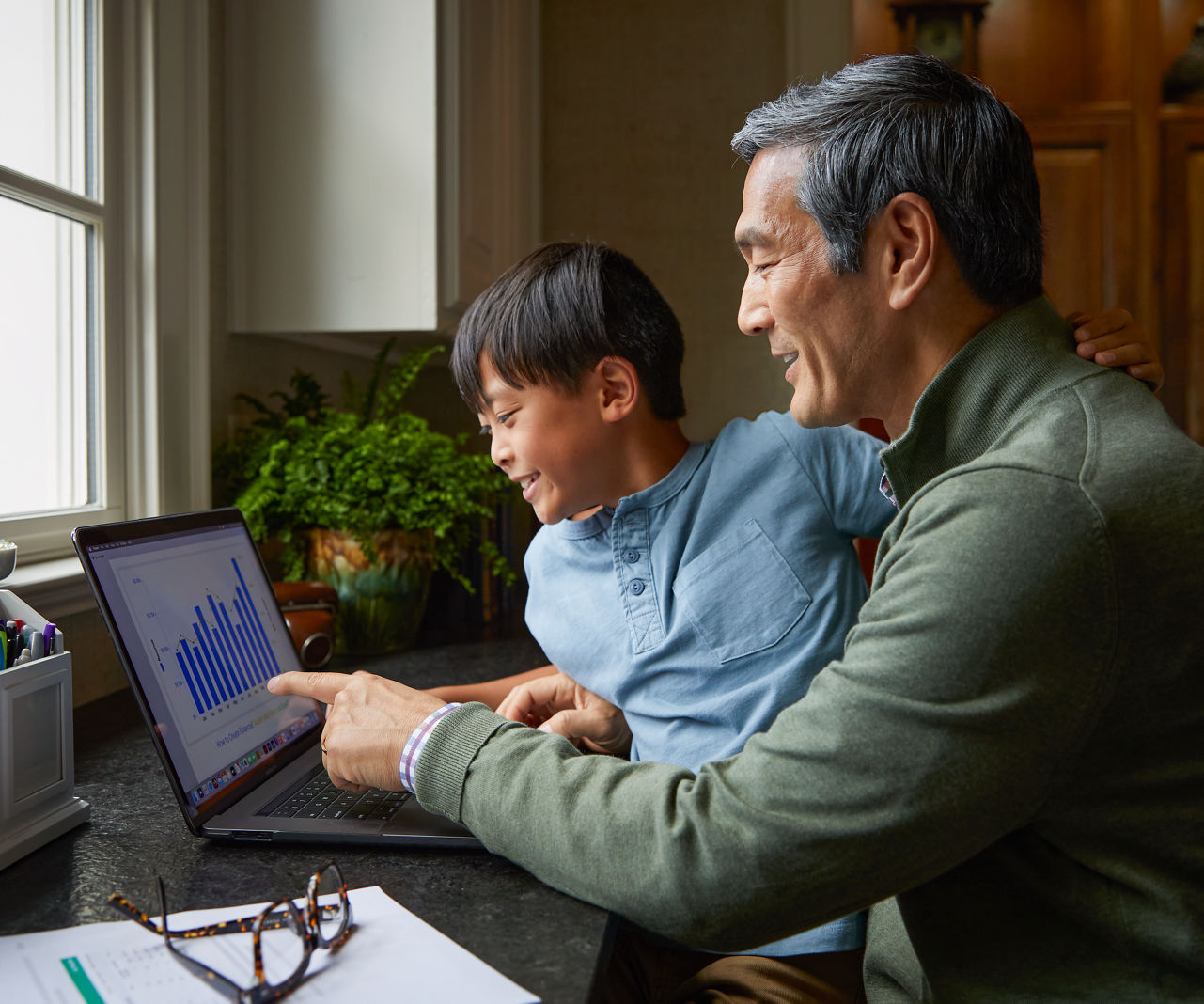 A man and a child smiling at a computer screen.