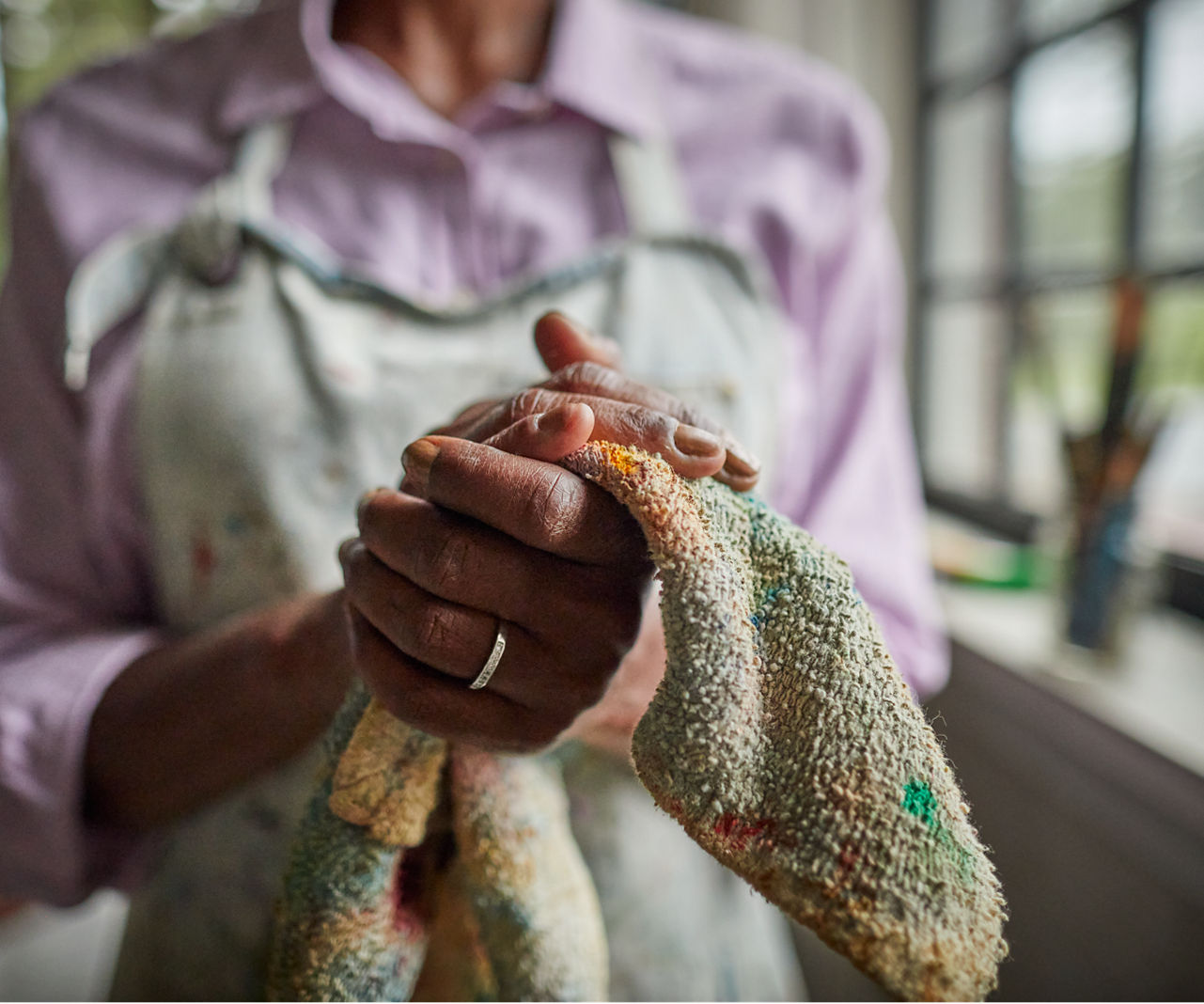 Woman wiping paint off of her hands with a cloth.