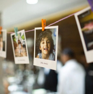 Snapshots of smiling children are hung on a string with colorful clothespins.
