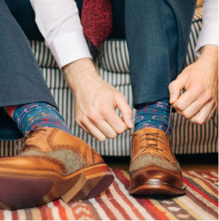 A business man ties wing tip shoes