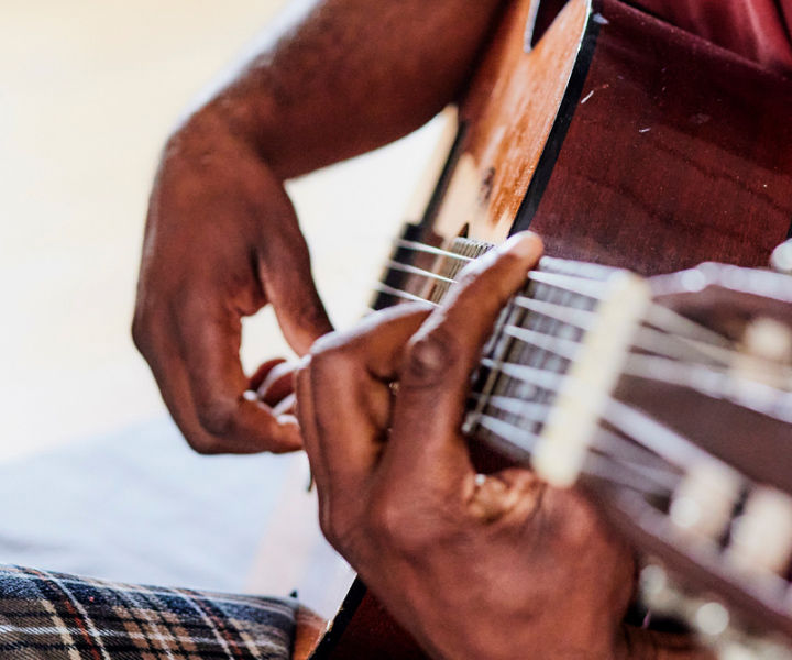 Close up of an older man's hands strumming a guitar.