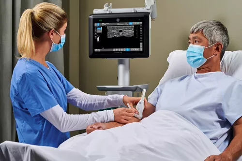 healthcare provider using a small ultrasound probe on a NICU/PICU patient
