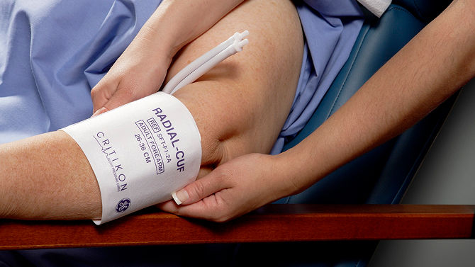 A clinician places a blood pressure cuff on a patient’s arm to measure vital signs.