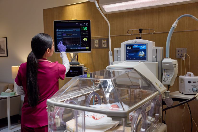 Nurse wearing a mask while holding an infant safely.