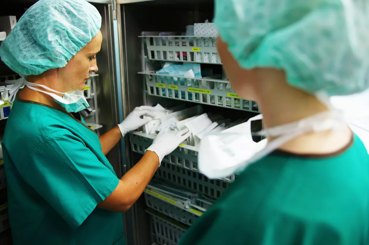 Operating_theatre_staff_wearing_scrubs_one_looking_through_supplies