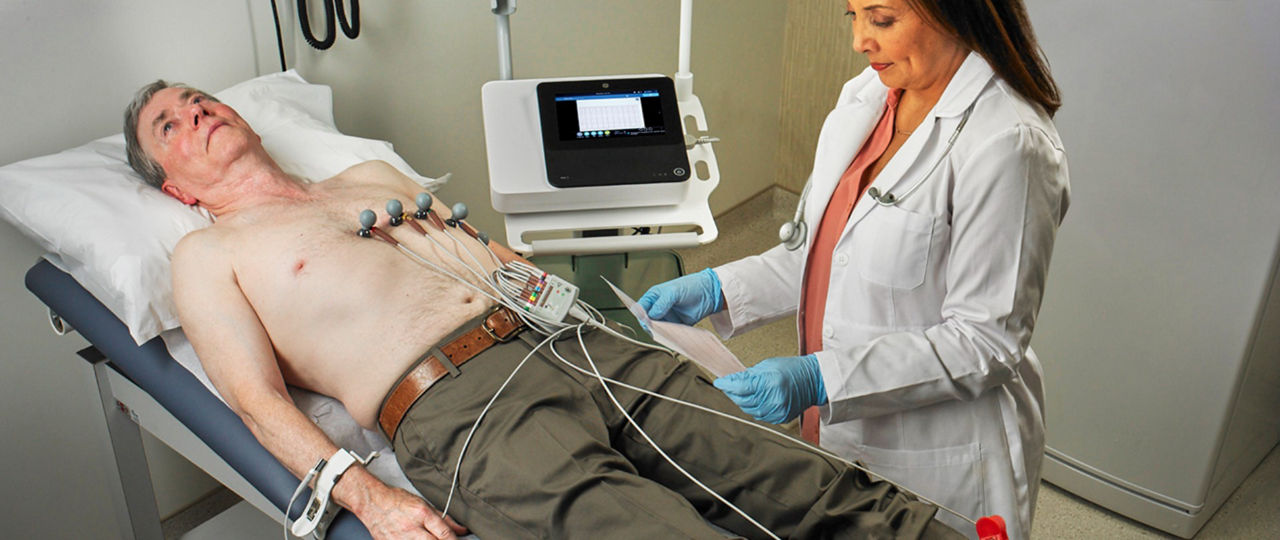 Physician_reviewing_ECG_from_man_lying_on_bed