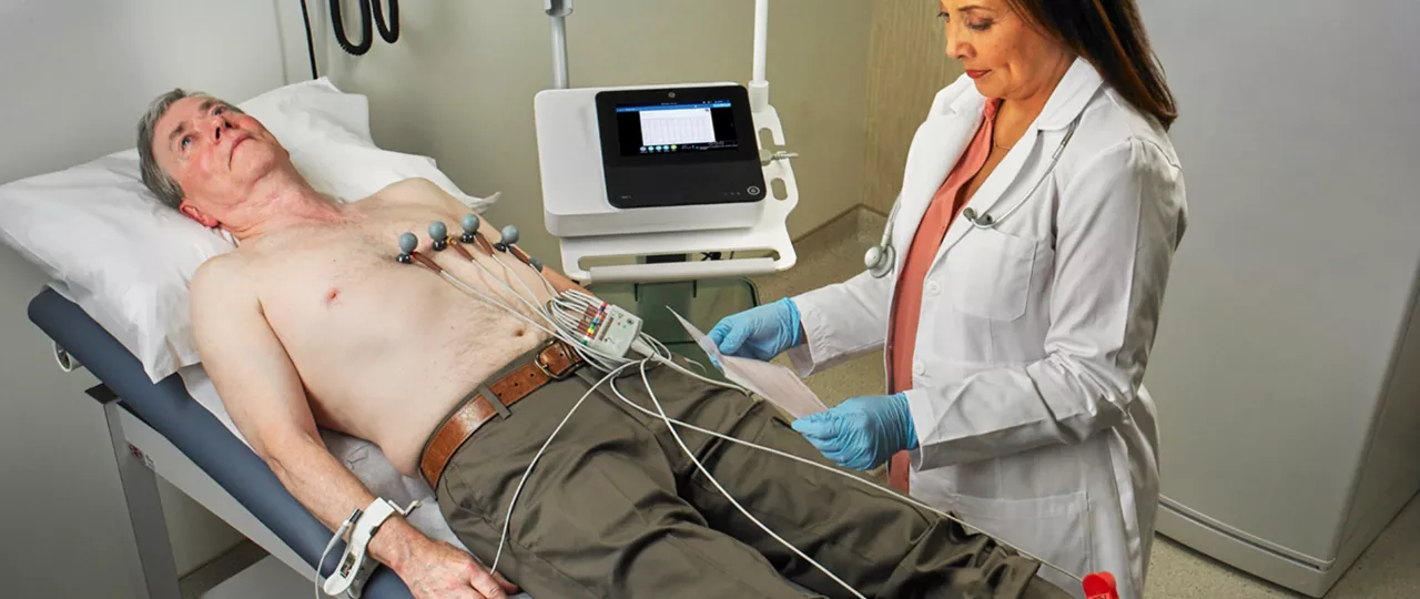 Physician_reviewing_ECG_from_man_lying_on_bed
