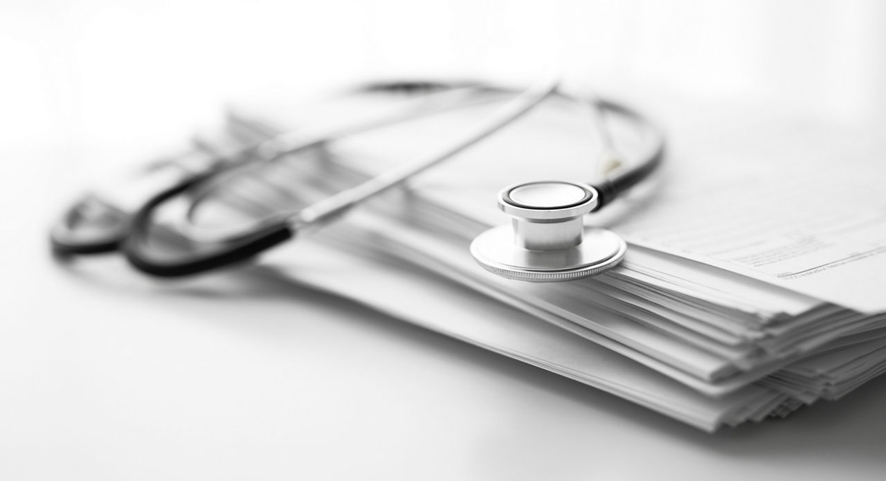 Stack_of_report_medical_documents_and_stethoscope_isolated_on_white_background
