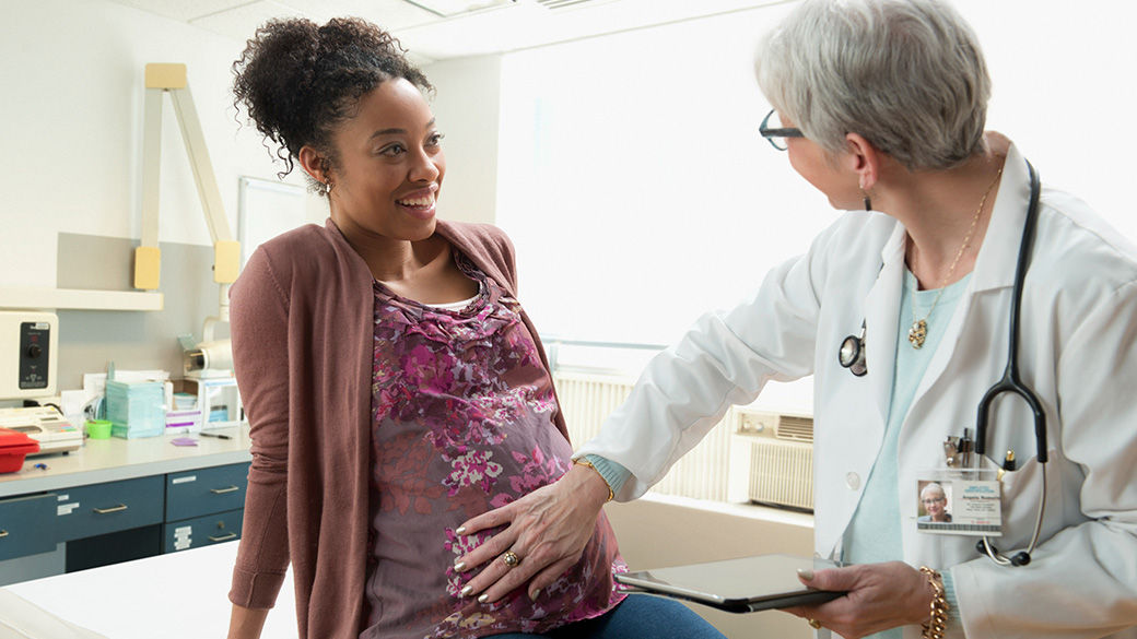 Clinician touching a pregnant patient's stomach