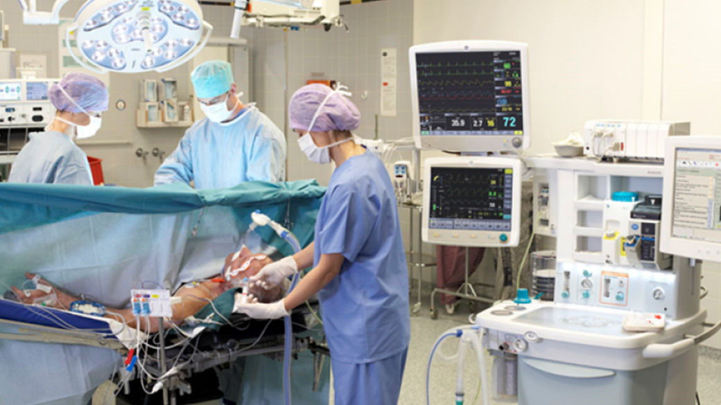 Three clinicians performing surgery on a patient