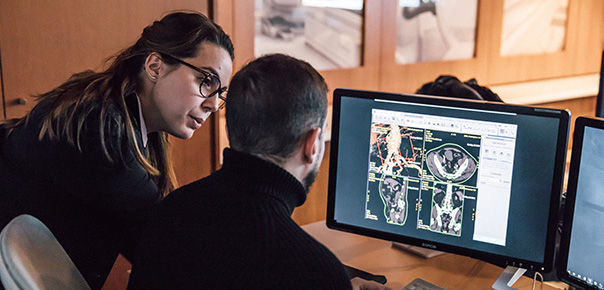 Two people looking at scans on a computer monitor
