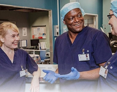3 healthcare workers in blue scrubs and talking and smiling