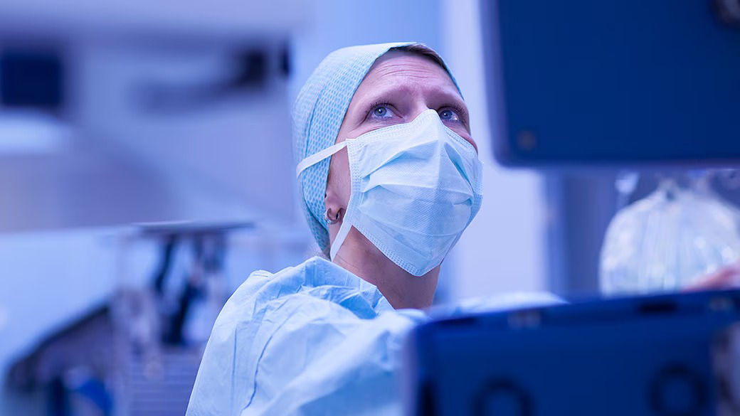 Physician wearing PPE in an OR looking at a monitor