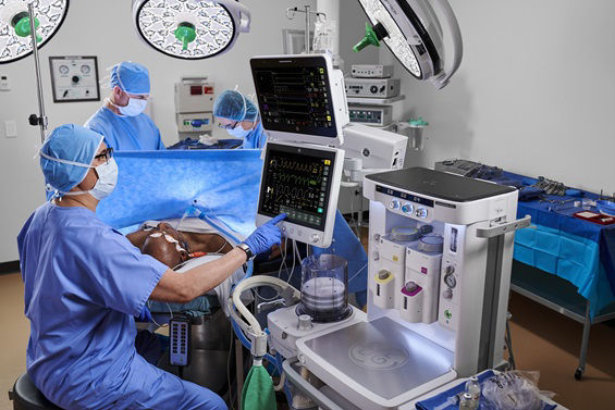 Clinician adjusting setting on a anesthesia machine in an operating room.
