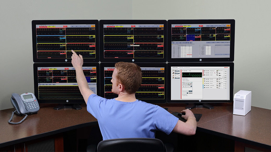Office worker using GE HealthCare's digital CMU at a desk with six computer monitors