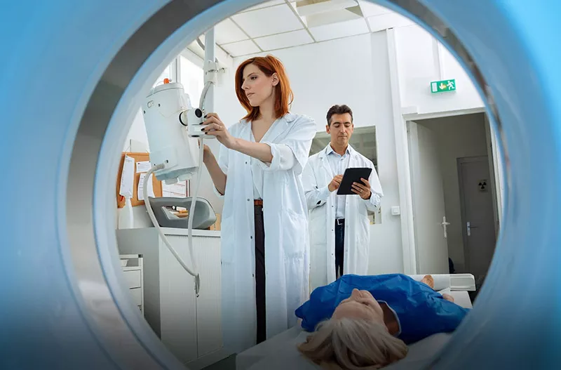 Two doctors getting a patient ready to enter an imaging machine