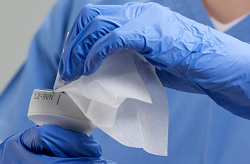 Healthcare worker disinfecting an imaging tool with a disinfectant wipe