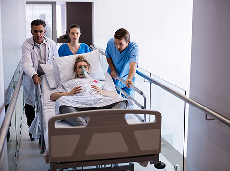 pregnant woman with an oxygen mask being wheel in a hospital bed by a doctor and two nurses