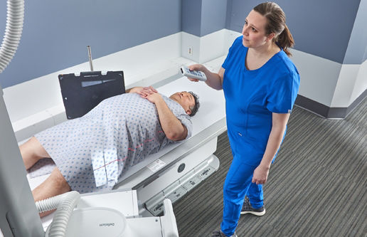 Definium656HD_Large Man on Table Cross Table Hip - with Technologists using remove to Auto position