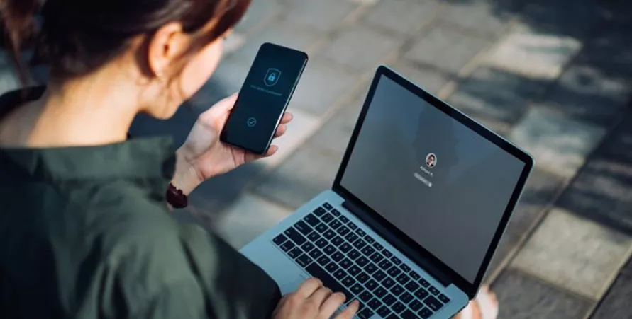 person using their laptop and their smartphone to safely access software