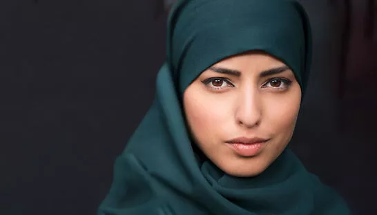 Woman faced directly at camera on black background