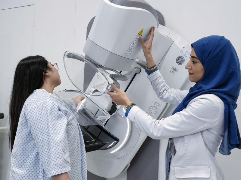 Medical professional in blue headscarf using medical equipment to scan patient's arm