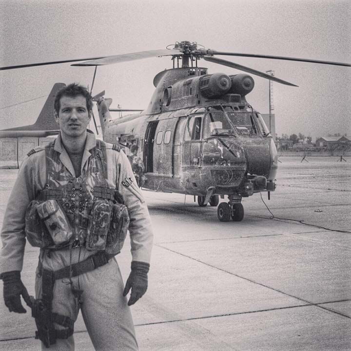 Mikey Kay in military clothing with helicopter on runway