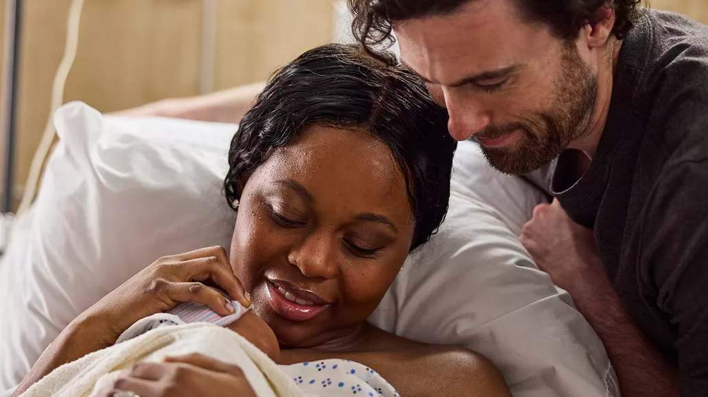 Parents with their newborn while a clinician provides care at the bedside.