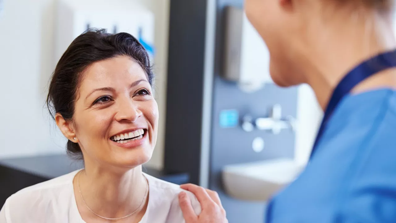 middle aged woman smiling and talking to a healthcare worker