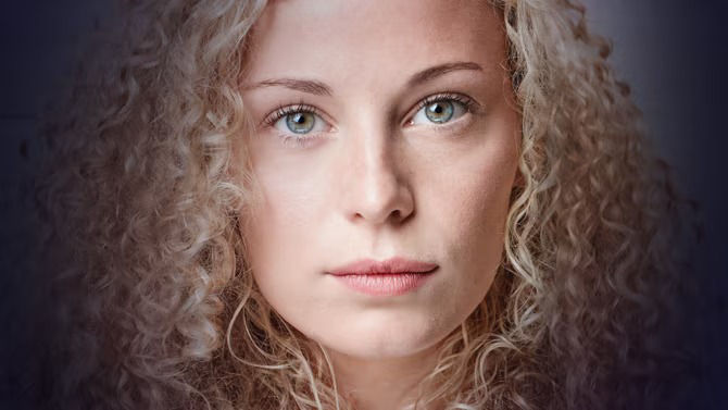 A young woman with curly hair faced directly at camera