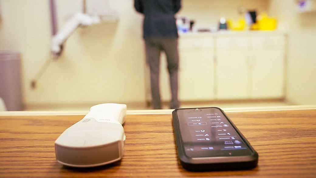 Handheld Utrasound with a doctor facing the opposite direction in the background