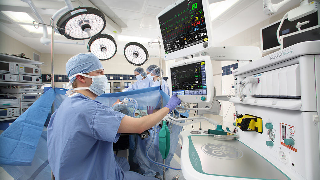 Surgeon in an operating room looking up at a dual patient monitors