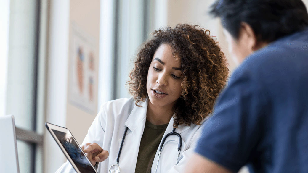 female doctor with curly hair showing colleague something on tablet