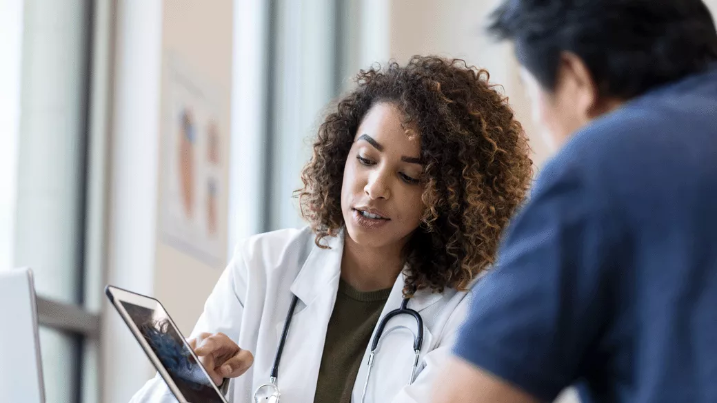 female doctor with curly hair showing colleague something on tablet
