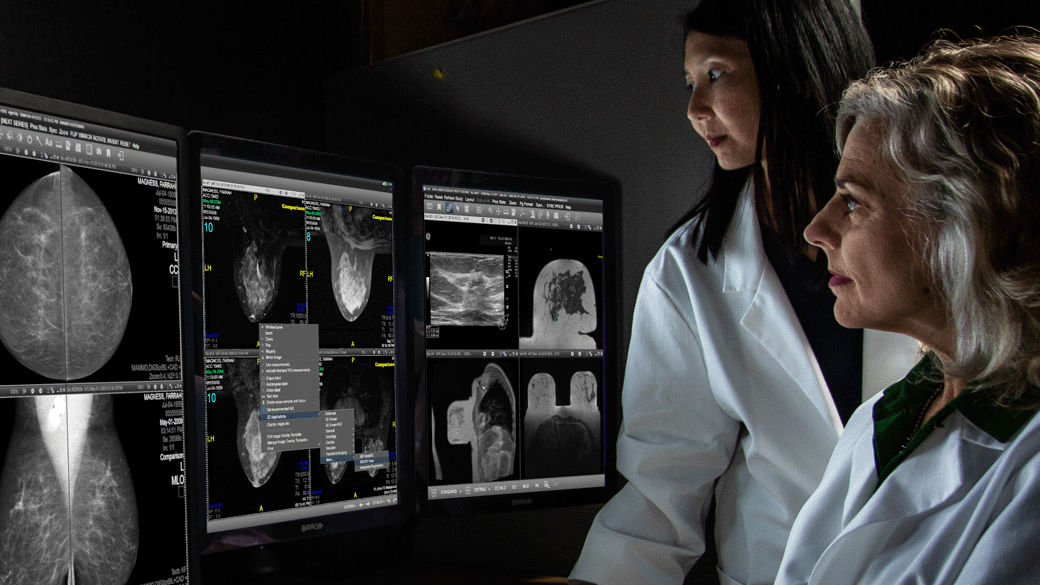 Two clinicians looking at computer monitors with scans on them