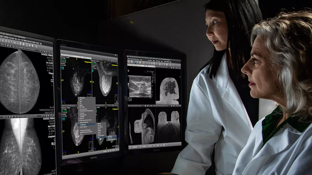 Two clinicians looking at computer monitors with scans on them