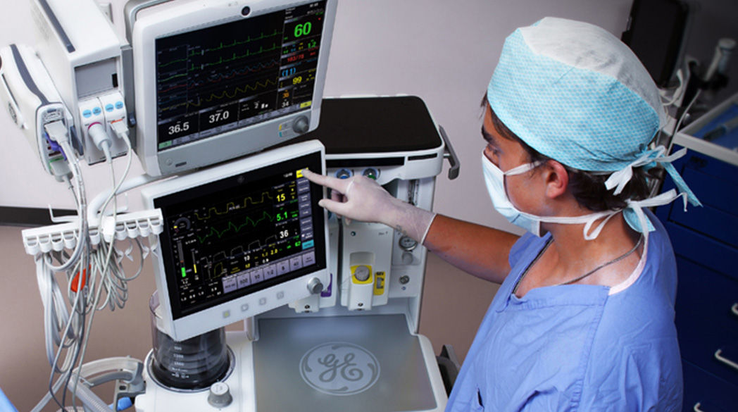 Clinician in full scrubs standing in front of the GE Carestation 600 series monitor system